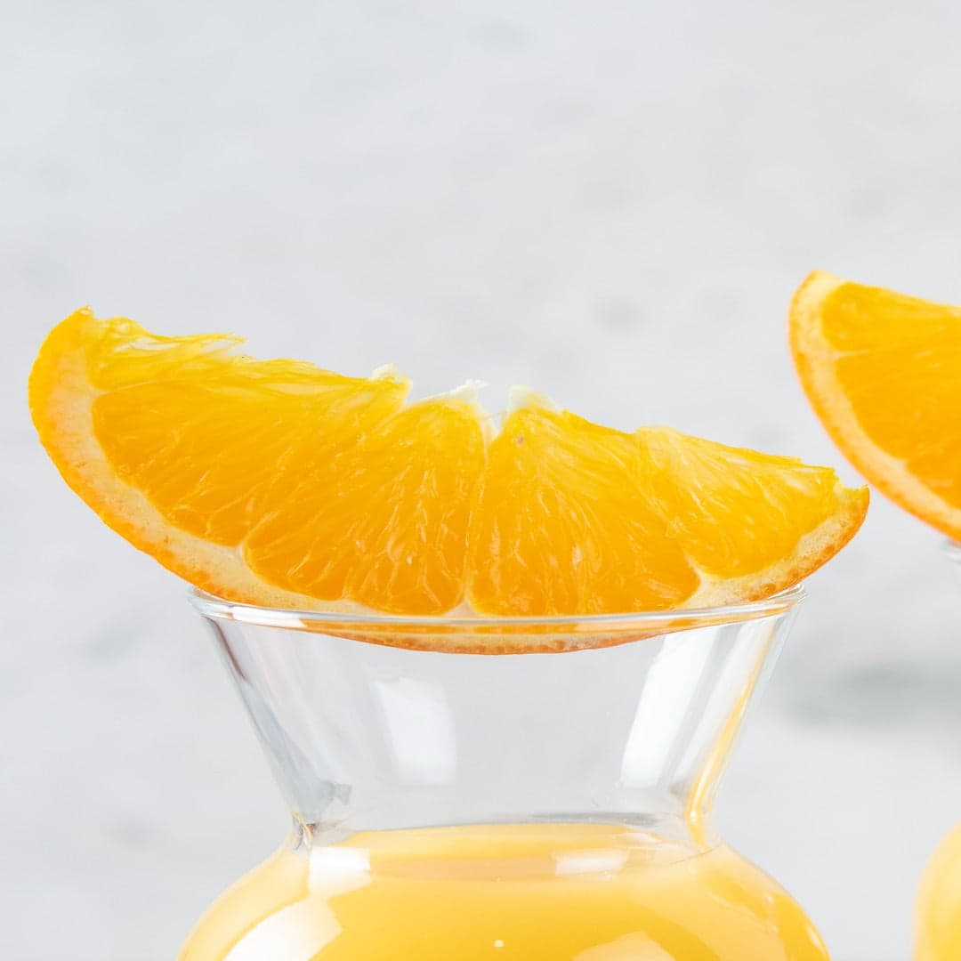 Freshly pressed orange juice in glass pitchers with orange slices
